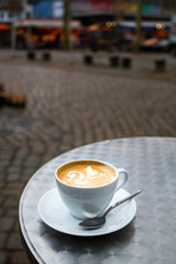 Cappuccino with beautiful latte-art with market in the background