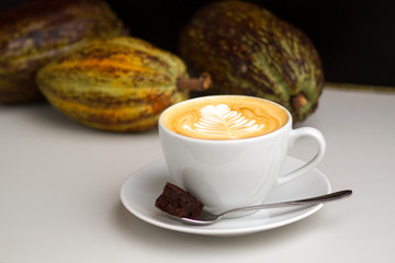 Cappuccino with beautiful latte art with cocoa beans in the background