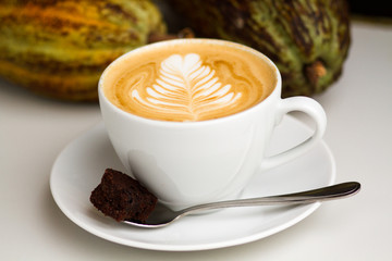Beautiful latte art on a cappuccino with cocoa beans in the background