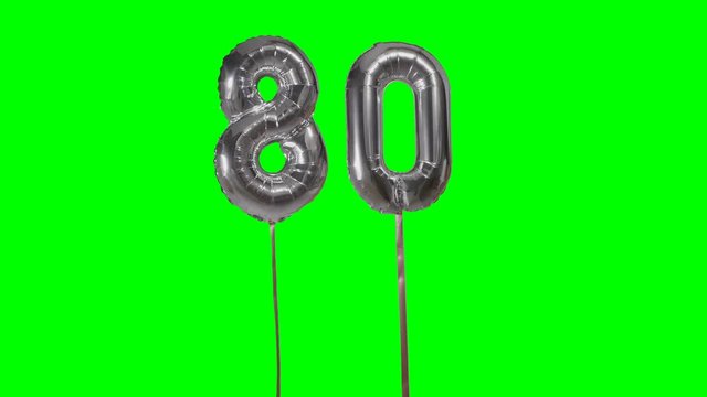 Number 80 eighty years birthday anniversary silver balloon floating on green screen