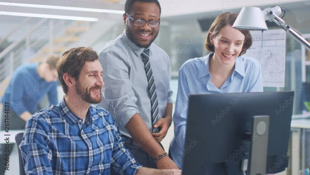 Poster In the Industrial Engineering Facility: Male Engineer Working on Desktop Computer, Female Chief Engineer and Project Manager Discuss and Explain to Him Project Details. They Smile, Joke and Cheer