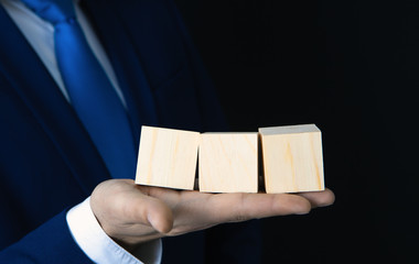 Businessman holding blank wooden cube.