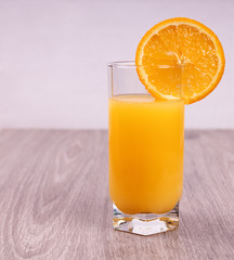glass with orange slice on light wooden background