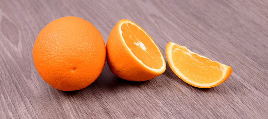 On a wooden background orange, half an orange and a slice