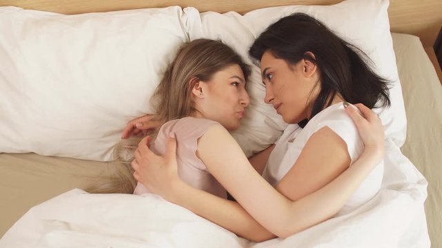 Lesbians having a nap, holding each other in a tender embrace. Top view cropped video.