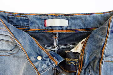 White blank tag on blue jeans, open zipper. Blank label inside women's jeans