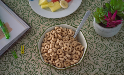 Cereal Cheerios Bowl with fruit and flowers over green background 