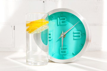 glass of water with lemon, alarm clock, measuring tape. the concept of a healthy lifestyle and...