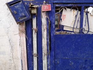 Rote Hausnummer, blauer Briefkasten und blaue Haustür eines baufälligen alten Haus im Sommer in...