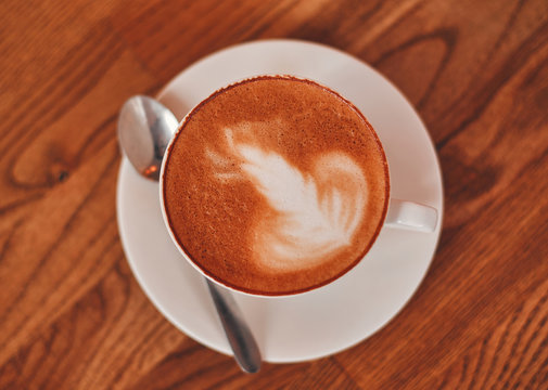 A cup of cappuccino on a wooden table