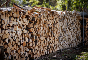 Stacked firewood of pine and birch prepared for the fireplace and stove in a large log woodpile in the yard.