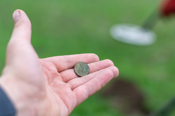 search for coins and treasure metal detector. man with a metal detector in a field looking for old coins with a metal detector. 