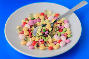 Pills served as a healthy meal. Drug capsule on white plate on blue background