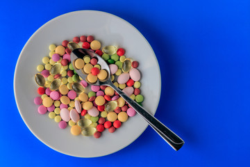 Pills served as a healthy meal. Drug capsule on white plate on blue background
