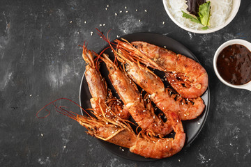 Fried grilled prawns with rice noodle, sauce and lettuce, dark background,copy space