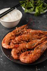 Fried grilled prawns with rice noodle and lettuce leaves, dark background, copy space