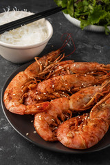 Fried grilled prawns with rice noodle and lettuce leaves, dark background, copy space