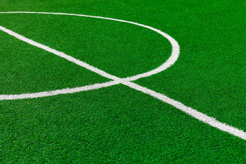 Fototapeta na wymiar Painted White Lines And Fragment Of Circle On Green Artificial Turf On Soccer Field. Center Of Football Fiels.