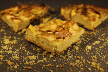 Pieces of apple pie on a grey background with crumbs