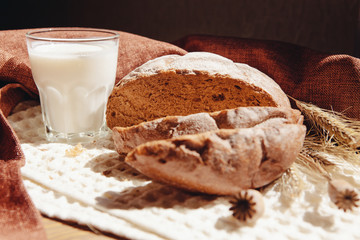 Fresh loaf of brown bread with milk or yogurt on table, beautiful healthy food