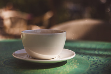 Coffee mug on mint green table outdoor background - soft light effect style pictures