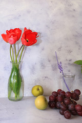 Grapes and a bouquet of flowers in a vase on a light background. Sunny start of the day, diet breakfast