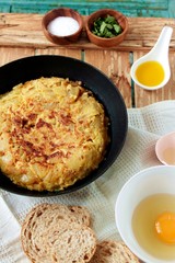 Tortilla de patatas y cebolla en la sartén sobre fondo de madera