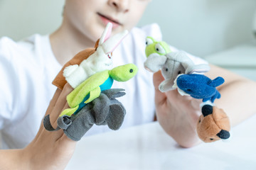 A caucasian boy playing different roles by using finger puppets, toys for expressing his emotions, agression, fear and freandship as a part of psychotherapy