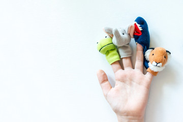 Hand of a child with finger puppets, toys, dolls close up on white background with copy space -...