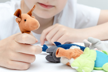A caucasian boy playing different roles by using finger puppets, toys for expressing his emotions,...