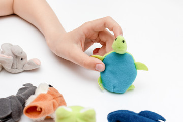 A caucasian boy playing finger puppets, toys, dolls - figures of animals, heroes of the puppet theatre put on fingers of human hand