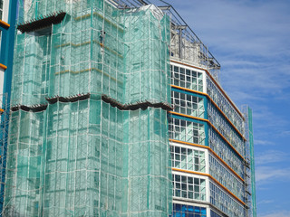 Catch platform and safety netting at the face of the building during high-rise building construction. It protects individuals and property from falling debris.  © Aisyaqilumar
