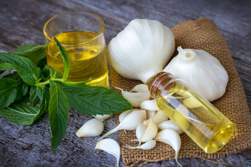 Fresh healthy garlic oil on the wooden background.