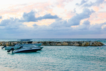 Fototapeta na wymiar Speedboats/ Motorboats docked on the beach at sunset on tropical Caribbean island. Holiday luxury resort setting. Vacation boat rentals.