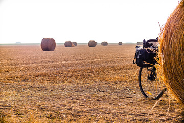 Touring bike hidden by a hay ball in a big orangee-colored field