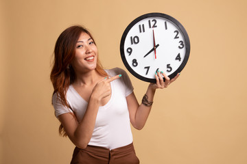 Young Asian woman point to a clock.