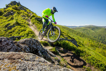 Professional athlete is riding enduro bicycle on a beautiful rocky trail.