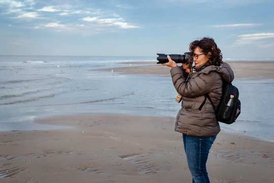 Beautiful middle-age Brazilian woman with taking pictures on a cold beach