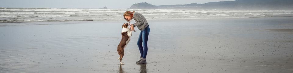 Panorama banner of a young woman and her dog on a California beach