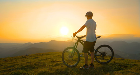 Fototapeta na wymiar LENS FLARE: Young male tourist observes the landscape before mountain biking