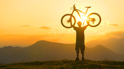 COPY SPACE: Bicycle rider celebrates finishing long cross country trip at sunset