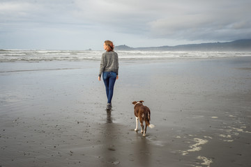 Young woman and her dog walking on the beach in Northern California