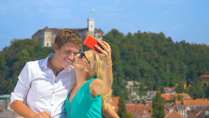 HANDHELD: Carefree girl kisses her boyfriend on the cheek while filming a v-log.
