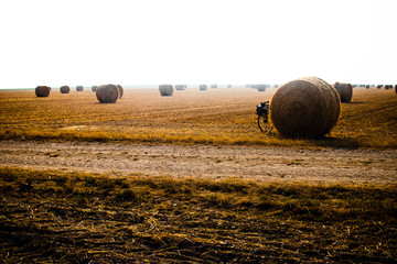 Touring bike hidden by a hay ball in a big orangee-colored field
