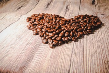 a handful of coffee beans in the shape of a heart, after roasting on the table, close-up. roasted heart-shaped coffee beans on the table, selective focus. Romantic theme.