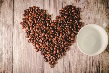 a handful of coffee beans in the shape of a heart, after roasting on the table, close-up. roasted heart-shaped coffee beans on the table, selective focus. Romantic theme.