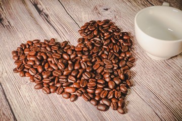 a handful of coffee beans in the shape of a heart, after roasting on the table, close-up. roasted heart-shaped coffee beans on the table, selective focus. Romantic theme.