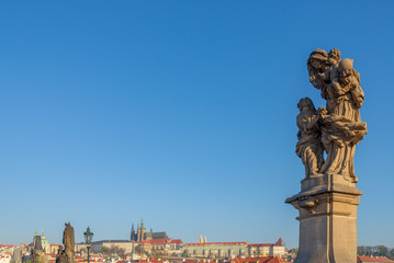 Fototapeta na wymiar Outdoor sunny view of the statue of Saint Anne stand on pedestal and balustrades of Charles Bridge over Vltava river, and background of Praha Castle in Prague, Czech Republic.
