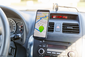 Arrival or destination point on the map in the phone on the dashboard background. Black mobile...