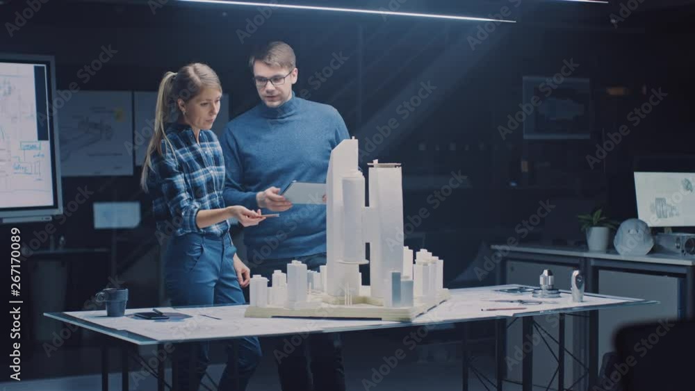 Poster in the creative architectural bureau two professional engineers work on a model of a city district. 